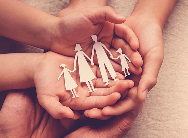 hands holding a paper doll family